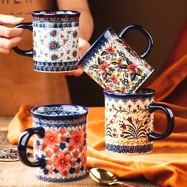 Eine Hand hält eine bunte, bohèmeartige Keramiktasse mit blau-weißen und rosa Mustern.
