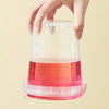 A hand is holding a clear plastic food grade milk tea storage bucket filled with pink liquid.