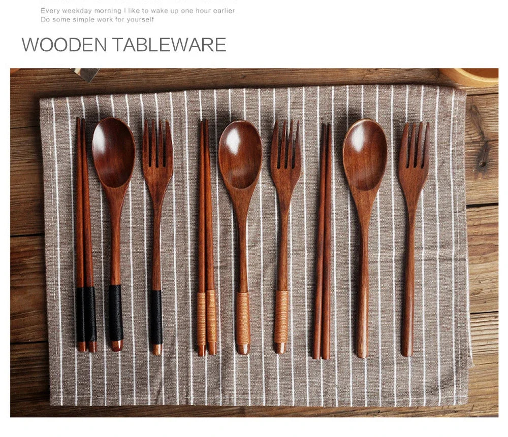 A set of natural wood dining utensils including spoons, forks, knives, and chopsticks laid out on a striped linen napkin.