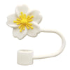 A white flower straw cap with a yellow sunburst design and a flexible plastic straw.