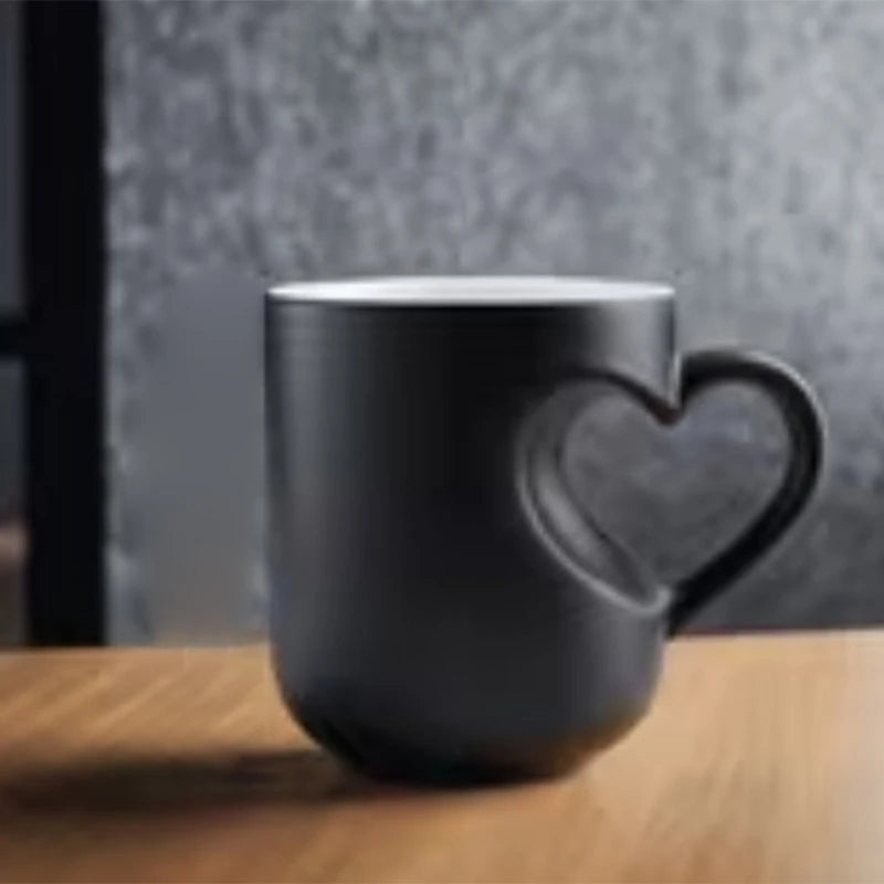A dark gray heart-shaped mug sitting on a wooden surface.