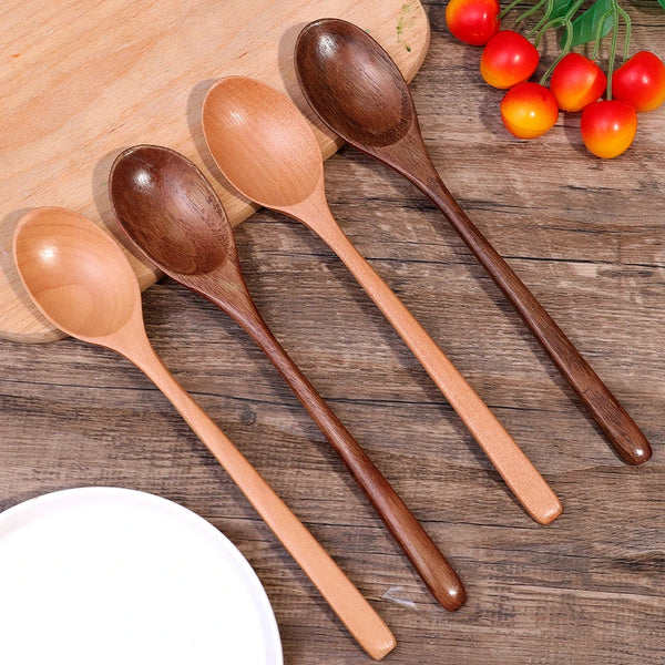 Ein Set hölzerner Küchenrührlöffel auf einem Holzbrett mit frischen Tomaten.