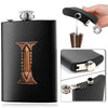A black stainless steel flask water bottle featuring an embossed leaf pattern, shown next to a dispenser and disassembled par