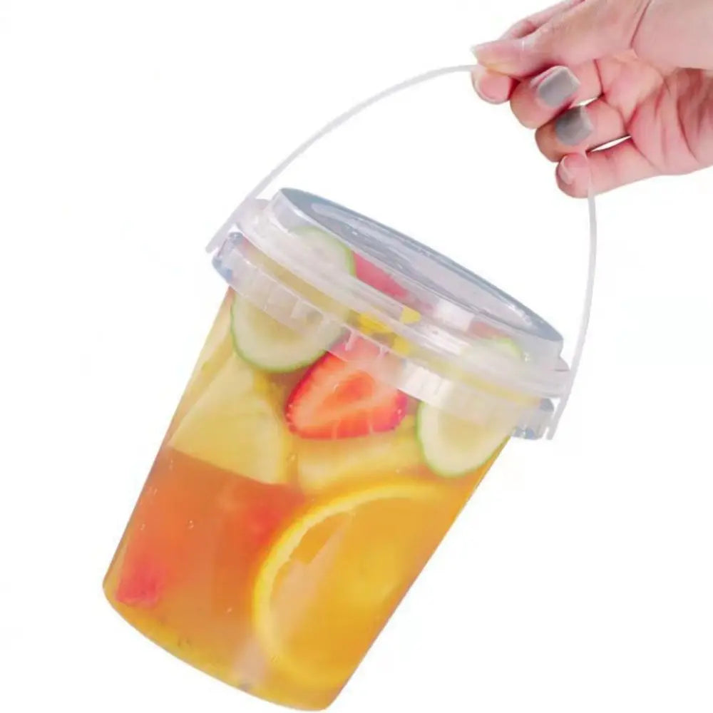 A hand holds a clear plastic milk tea storage bucket filled with fruit slices and liquid.