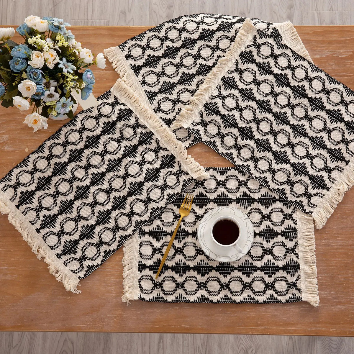 Boho Platzsets mit schwarz-weißer Musterung und natürlichen Baumwollfransen auf einem Holztable