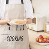 A person wearing an apron is holding a white plate with baked goods, demonstrating reusable food storage bags.