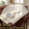 A clear mesh foldable cover is placed over a wooden table, demonstrating various sizes for food and plant protection.