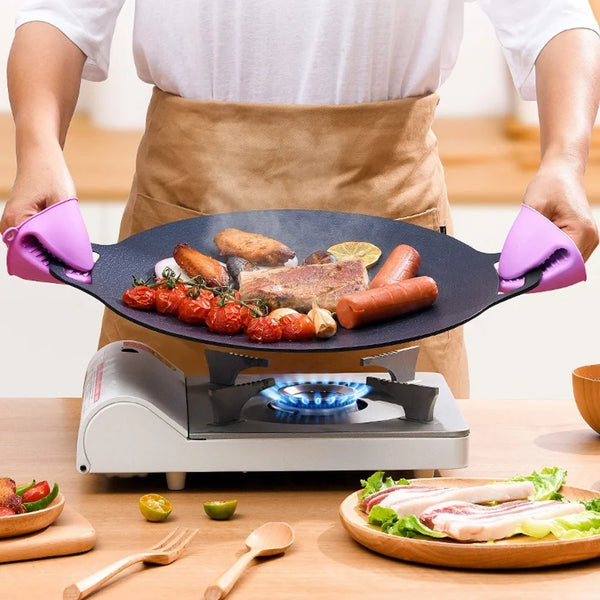 Eine Person hält eine antihaftbeschichtete Marmor-BBQ-Grillpfanne mit Griff, die Kochoberfläche und umgebende Zutaten zeigt