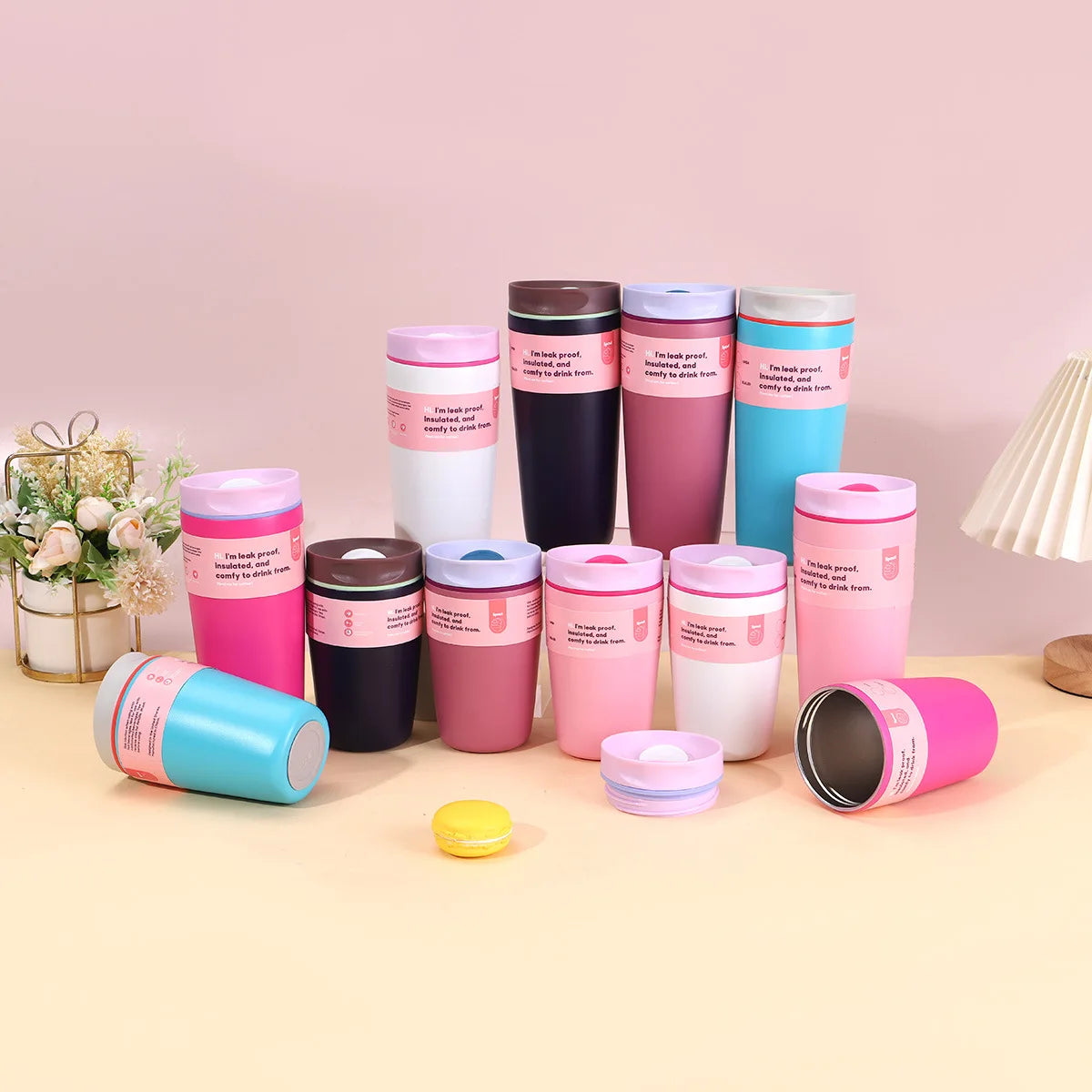 A collection of pink, purple, and blue stainless steel vacuum coffee mugs arranged on a light surface.
