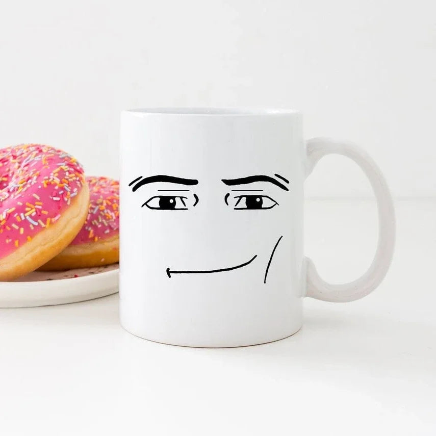 A white ceramic coffee mug featuring a simple black line drawing of a slightly annoyed or skeptical face.