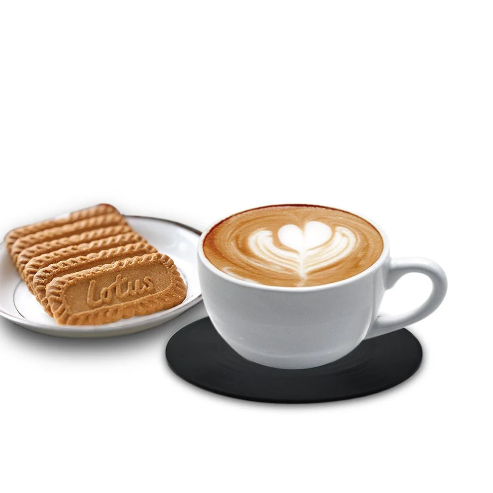 A white ceramic cup of latte art coffee sits on a black saucer next to a stack of round, tan vinyl record coasters.