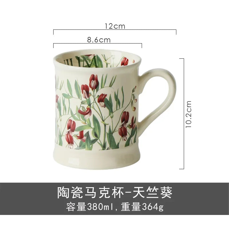 A ceramic coffee mug featuring a floral pattern of red and green leaves.