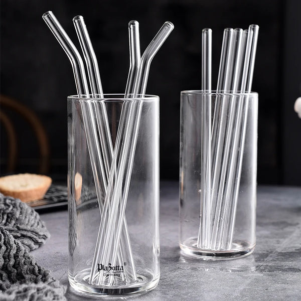 Klare Glasstrohhalme werden in zwei Gläsern auf einer grauen Oberfläche präsentiert.