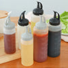 A collection of clear glass squeeze seasoning dispenser bottles in various shades of amber and brown sitting on a wooden surf