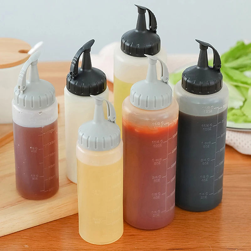 A collection of clear glass squeeze seasoning dispenser bottles in various shades of amber and brown sitting on a wooden surf