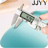 A hand holds a silver kitchen drainer colander with a digital scale displaying 4.14 inches.