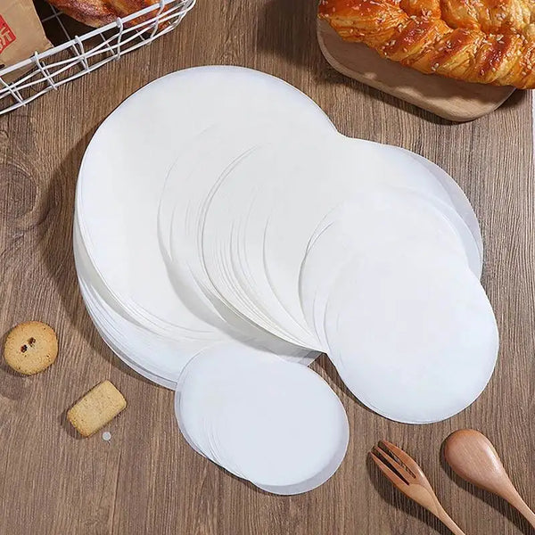 Eine Stapel weiße runde Backpapierfolien auf einer Holzoberfläche mit kleinen gelben Cracker.