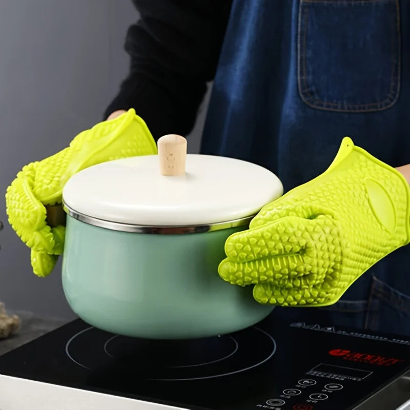 A pair of bright lime green silicone heat resistant kitchen and BBQ gloves resting on a cooking surface.