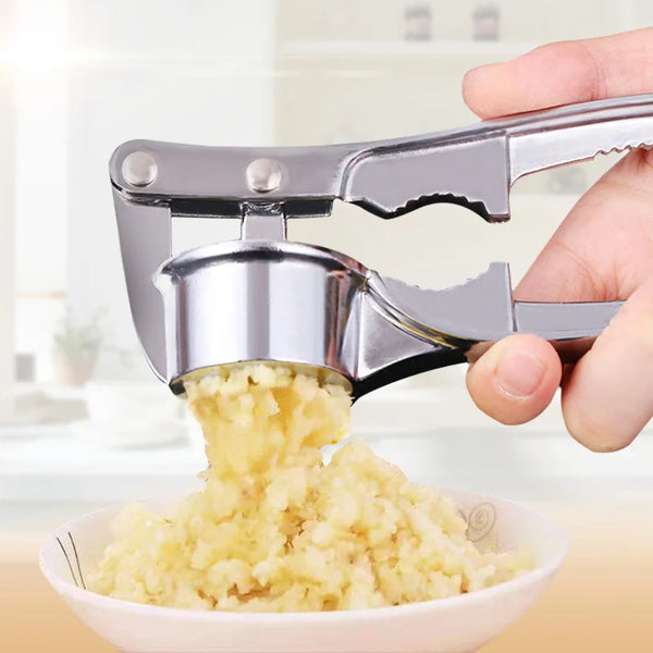 Eine Hand drückt gehackten Knoblauch mit einem Edelstahl-Knoblauchpresse und -Reibe in eine weiße Schüssel.