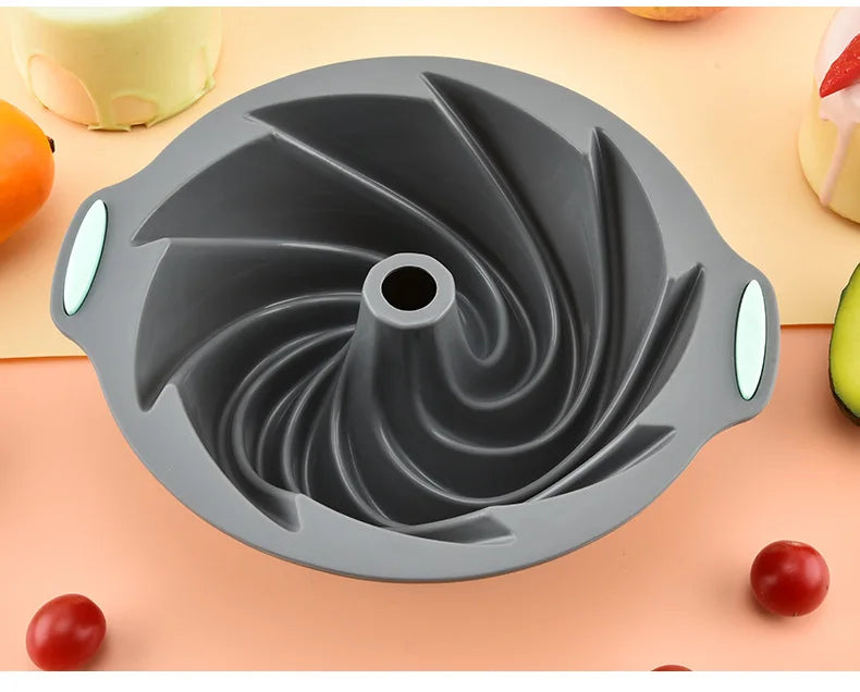 A gray silicone baking mold with a swirling design is shown on a light orange surface.
