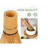 A handcrafted bamboo matcha whisk being used to prepare tea in a white bowl.
