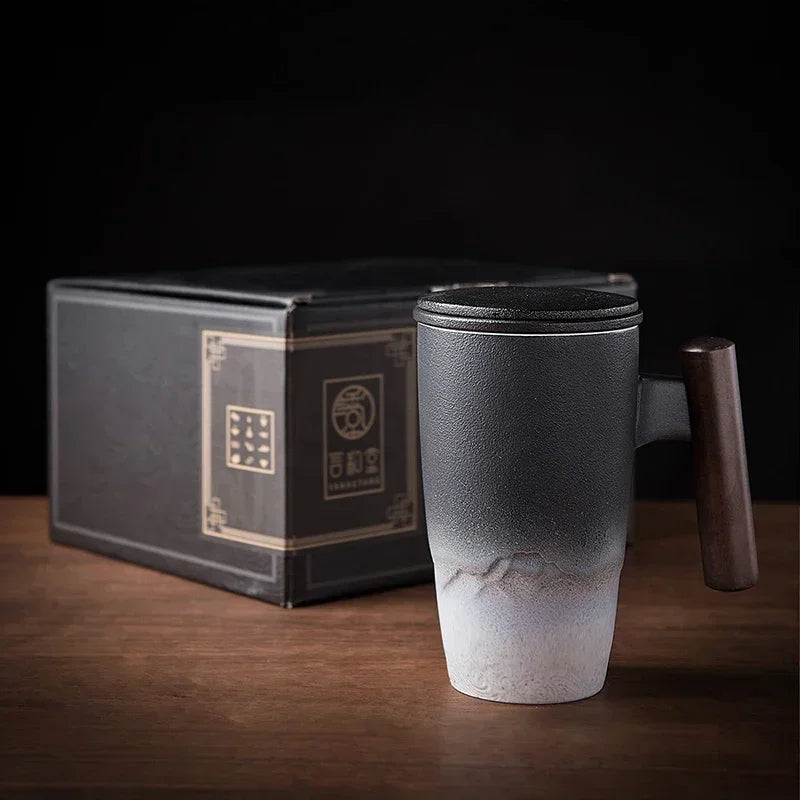 Una taza de té de cerámica oscura con mango de madera sobre una superficie de madera junto a su caja.