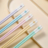 A set of reusable Japanese Chinese chopsticks in various pastel colors laid on a light beige plate.