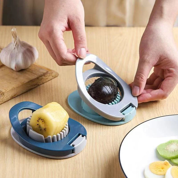 Hände benutzen einen Edelstahl-Eierslicer und Fruchtcutter, um eine Frucht auf einem Holztablett zu schneiden.