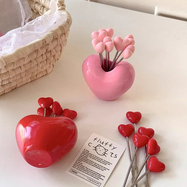 A set of red heart-shaped stainless steel forks for fruit and dessert
