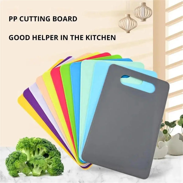 Ein Stapel farbenfroher Kunststoff-Cutting Boards, darunter einer dunkelgrauen, neben frischem Brokkoli.