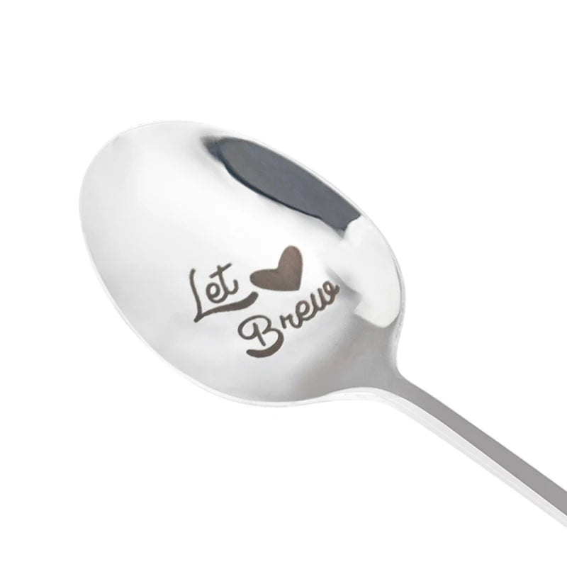 A silver stainless steel spoon with the words Let Brew engraved on it.