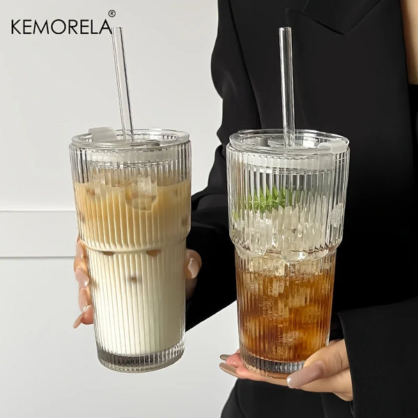 A clear glass coffee cup filled with iced latte, held by a person, featuring a striped texture.