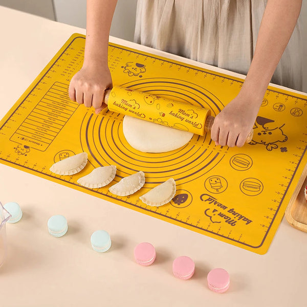 Eine Hand rollt Teig mit einem gelben Silikon-Nudelmesser auf einer gelben Backmatte.