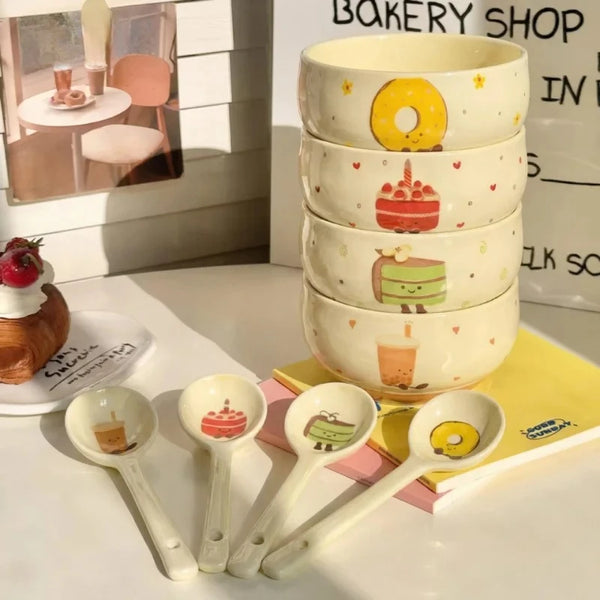 Set süße Keramiksuppenschalen und Löffel mit Figuren wie einer Zitrone und einem Kuchen.