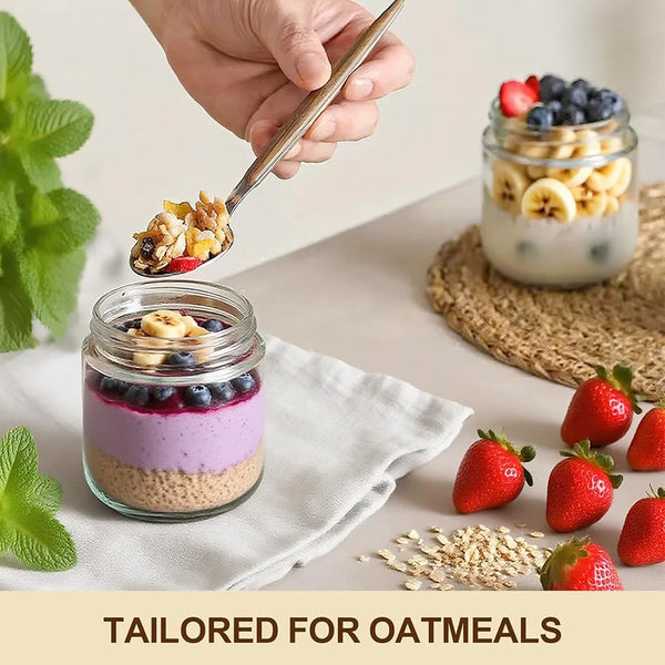 A hand uses a spoon to scoop oatmeal into an airtight glass jar, with fresh strawberries and oats nearby.
