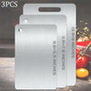 Three stainless steel double-sided cutting boards in varying sizes displayed on a wooden surface.