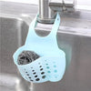 A light blue adjustable sink drain hanging sponge rack with a mesh holder is visible on a stainless steel kitchen sink.