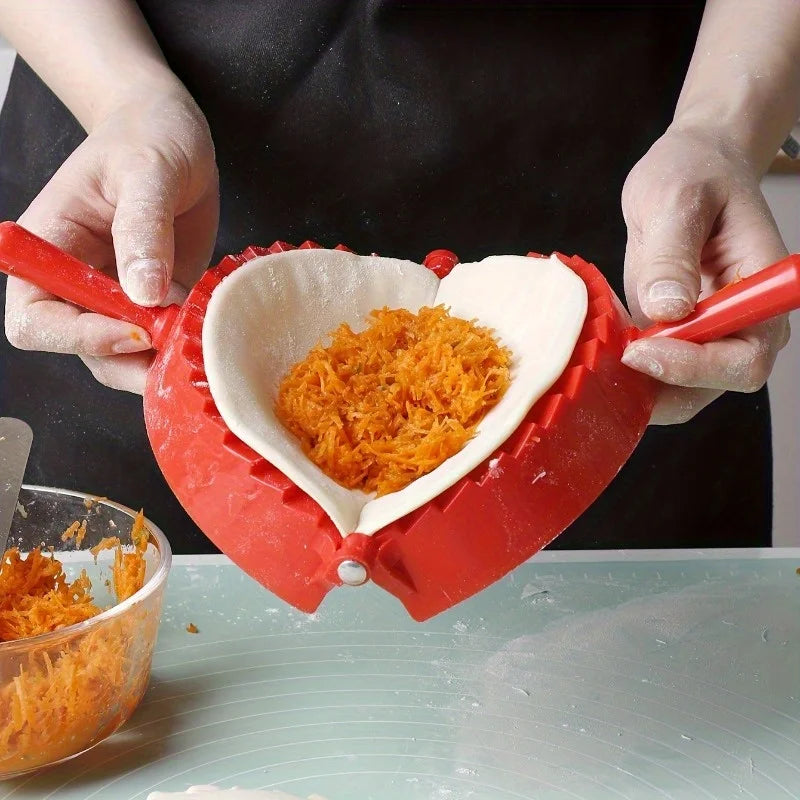 Hands are pressing orange shredded material into a red manual dumpling press for homemade pastries.