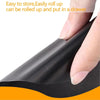 A hand is rolling up a black reusable non-stick oven and grill liner for easy storage.