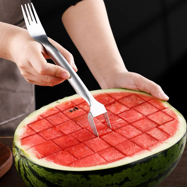 Eine Hand benutzt ein Edelstahl-Obstslicer- und Ballerwerkzeug, um einen Querschnitt einer Wassermelone zu schneiden.