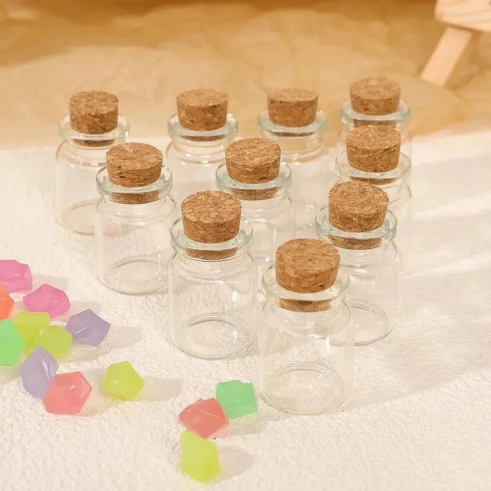 A set of decorative glass bottles filled with dried herbs or seeds, arranged on a white cloth.