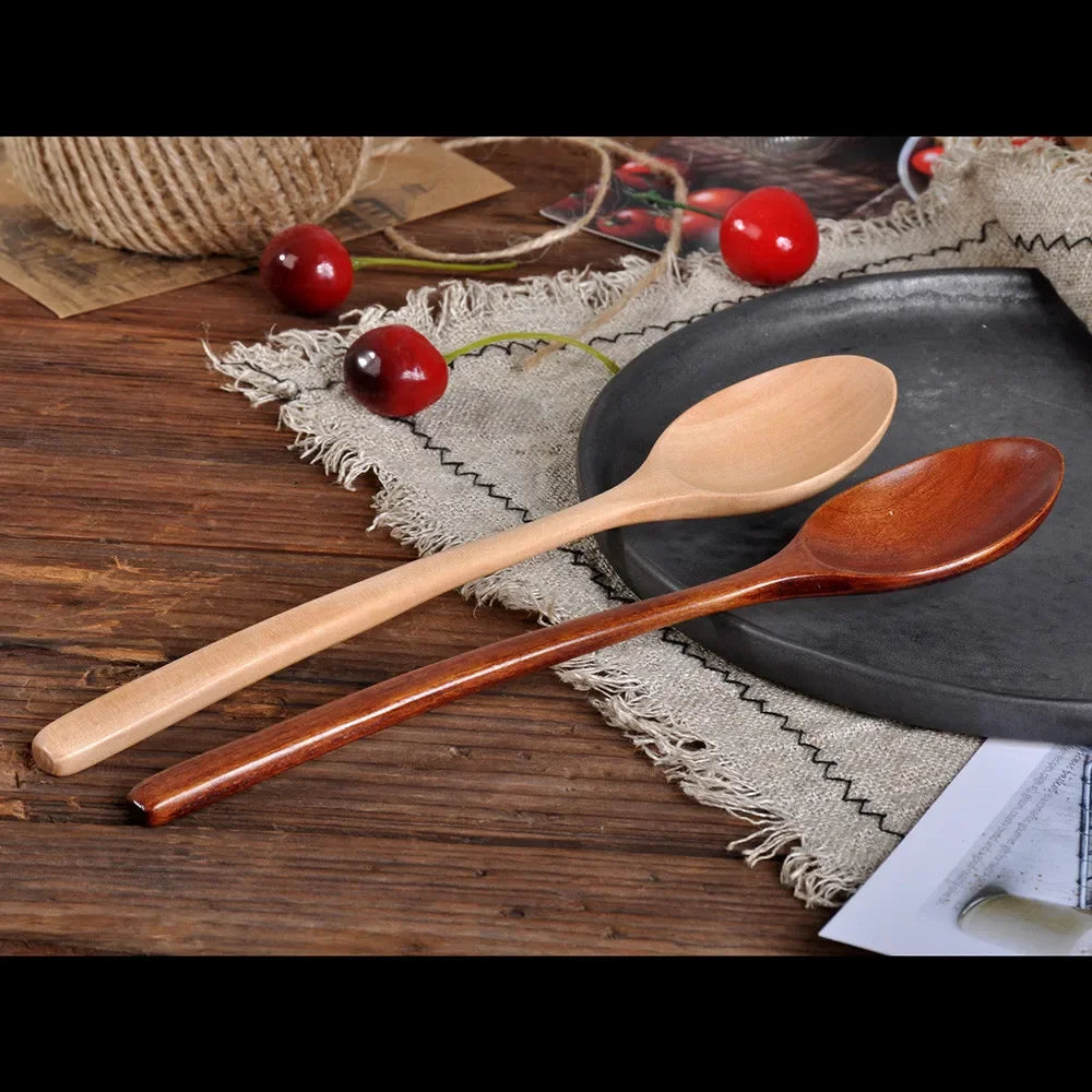 A set of three wooden spoons resting on a dark plate with red berries on a rustic wooden surface.