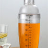 A clear plastic cocktail shaker bottle filled with orange liquid, showing volume markings and a silver cap.