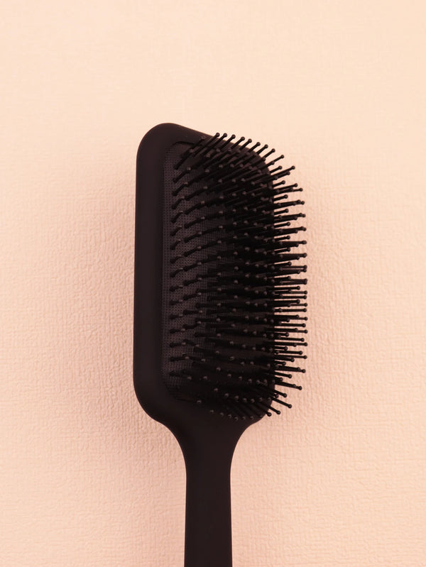 A black anti-static plastic scalp massage comb is shown against a light background.