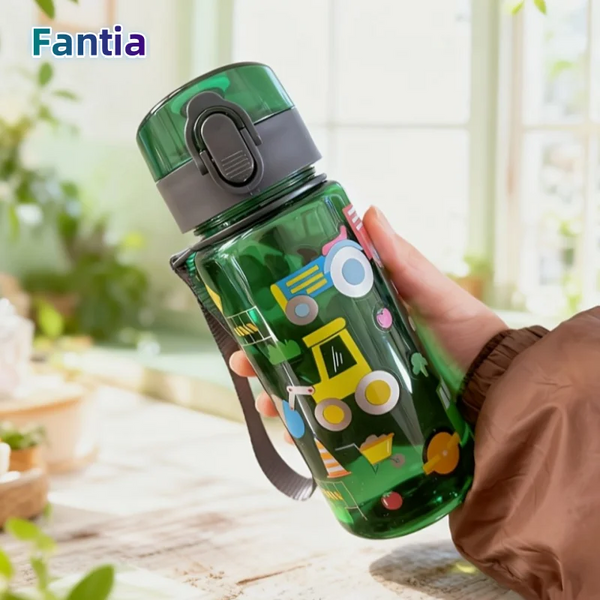 A hand holds a green plastic water bottle with a cartoon pattern against a bright background.