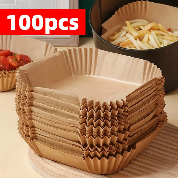 Ein Stapel von 100 Backpapier-Liner für Antihaft-Airfryer-Einsätze neben einer dunklen Kochpfanne.