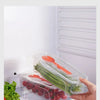 A clear plastic container holds green vegetables and an orange fork inside a microwave cooker compartment.