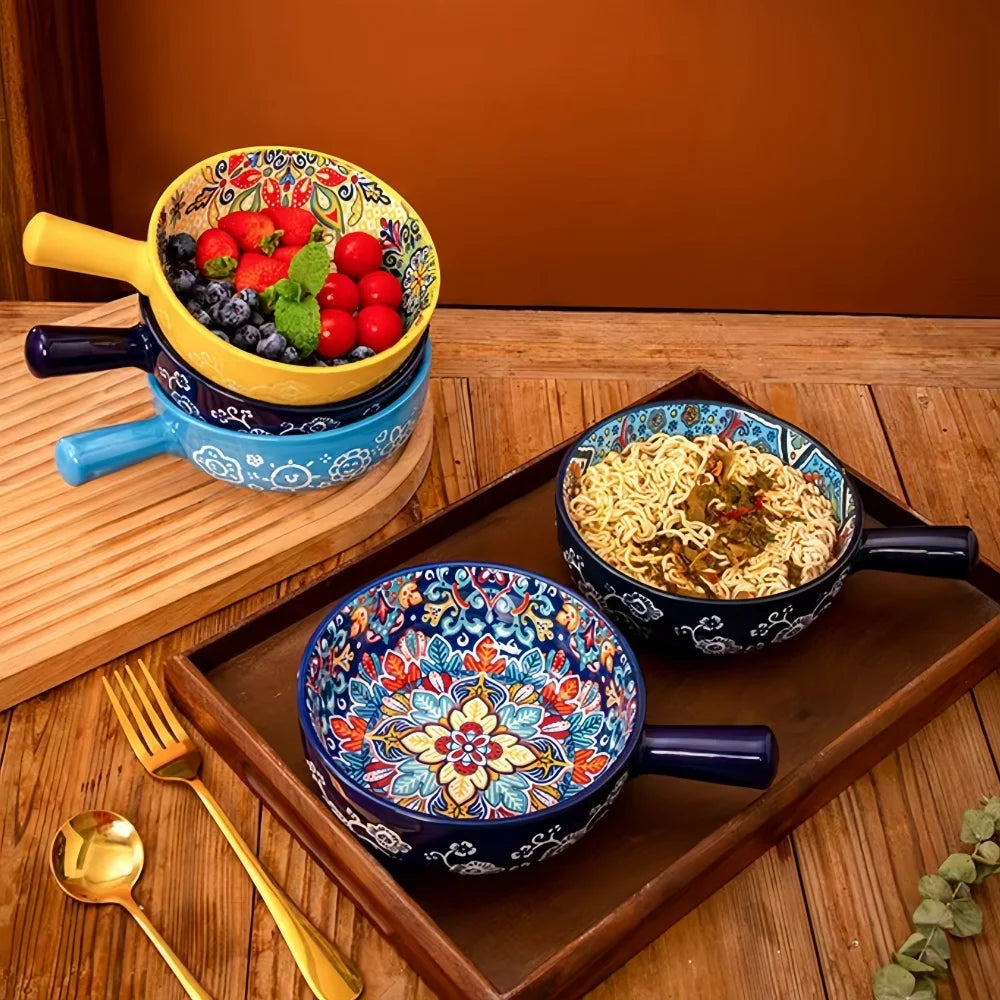 A wooden tray holds hand-painted ceramic salad bowls and gold cutlery against a brown background.