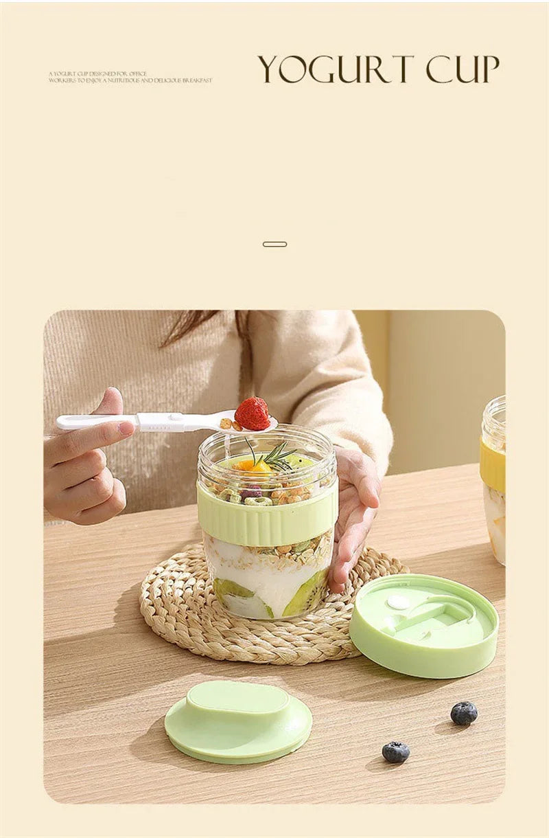 A glass yogurt cup with fruit and a lid is shown on a wooden table next to a bamboo mat.
