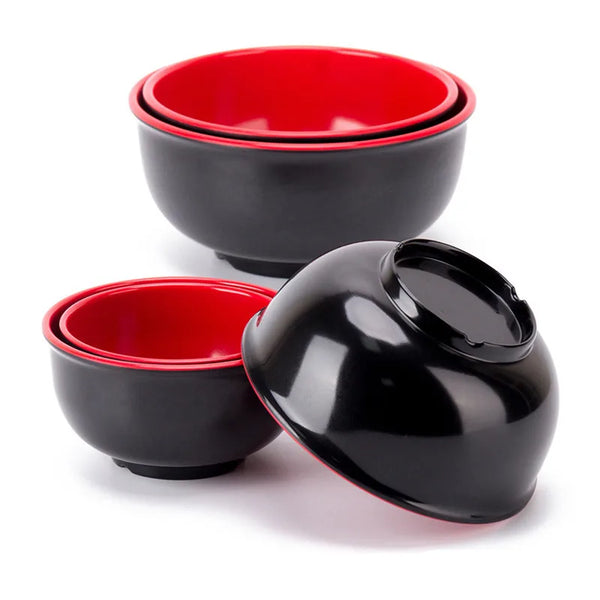A set of black melamine soup and rice bowls with red rims.